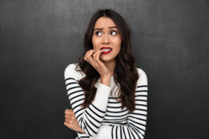 Woman biting her nails and worrying about cosmetic dentistry